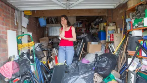 Exasperated woman standing in the middle of an overfilled, unorganized garage