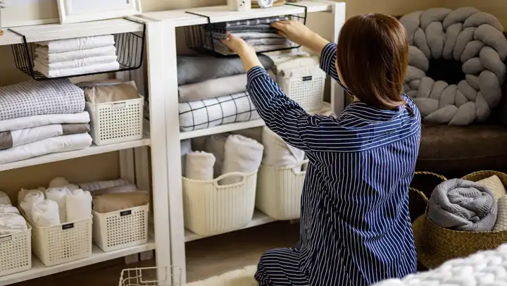 A woman organizes a linen shelf