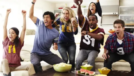 Friends watching football in their living room with snacks